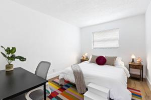 a white bedroom with a bed and a table at Stylish 2 BR Condo - Free Parking on Premises in Fort Lauderdale
