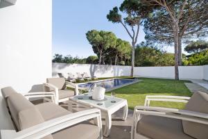 een patio met witte stoelen en een zwembad bij Villa moderna en Chiclana in Chiclana de la Frontera