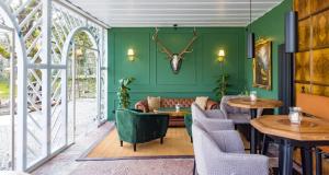 um restaurante com paredes verdes, mesas e cadeiras em Der Schlosswirt zu Anif - Biedermeierhotel und Restaurant em Anif