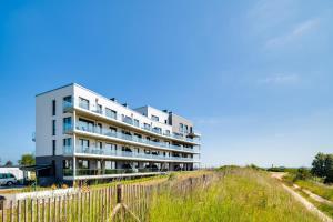 um edifício de apartamentos numa colina com uma cerca em BeachTerraceOne - EG, Meerblick, Terrasse, Kamin, Sauna em Olpenitz