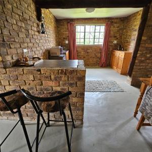 een woonkamer met een bakstenen muur en een stoel bij Villa Dachie in Rayton