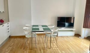 a dining room table with white chairs and a television at Apartamento San Agustín- Centro in Granada
