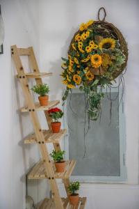 une couronne suspendue sur un mur avec des fleurs sur une étagère dans l'établissement TARANTA HOUSE - Notte della Taranta casa con giardino, à Melpignano