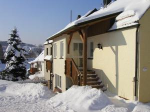 Una casa con nieve al costado. en Ferienwohnung Frosch, en Bischofsgrün
