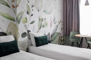 デン・ハーグにあるコー​​ト ガーデン ホテル エコデザインドのベッド2台と壁画が備わるホテルルームです。
