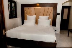 a bedroom with a white bed with a wooden headboard at Romantic garden hotel in Negombo