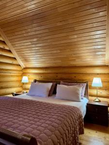 1 dormitorio con 1 cama grande y paredes de madera en Cottage PolyaNitsa окремий котедж з каміном en Bukovel