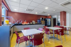 um restaurante com mesas brancas e cadeiras vermelhas em City Express Junior by Marriott Tuxtla Gutierrez Poliforum em Tuxtla Gutiérrez