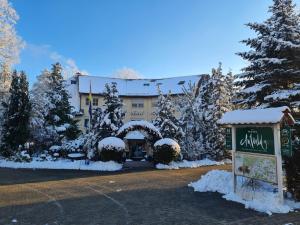 a building covered in snow with a sign in front at Hotel Am Wald B&B in Michendorf