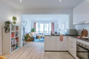 eine Küche mit weißen Schränken und ein Wohnzimmer in der Unterkunft Colorful apartment in the heart of Antwerp in Antwerpen