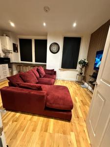 a living room with a red couch and a clock at 2 bed Home away from home tooting London in London