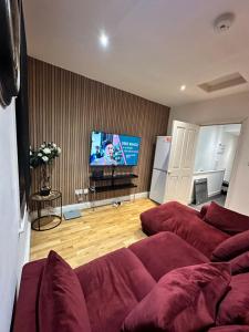 a living room with red couches and a flat screen tv at 2 bed Home away from home tooting London in London