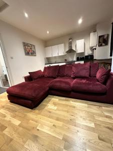 a large red couch in a living room at 2 bed Home away from home tooting London in London