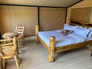 a bedroom with a bed in a tent with a chair at OLORIEN MARA CAMP in Masai Mara