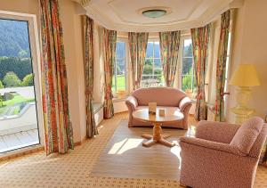 un soggiorno con sedie, tavolo e ampia finestra di Ailwaldhof Parkhotel & Spa a Baiersbronn