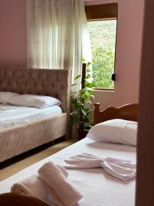 2 Betten in einem Schlafzimmer mit Fenster in der Unterkunft Vjosa Guest House in Memaliaj