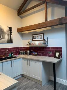 eine Küche mit weißen Schränken und roten Fliesen in der Unterkunft Studio 3B The Carriage House York 6m Village Location in York