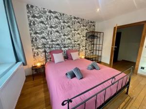 a bedroom with a pink bed with two pillows at Gite Pays de Herve - Emeraude in Battice