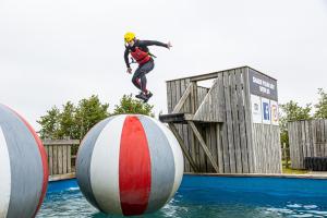un homme faisant du skateboard sur une balle dans l'eau dans l'établissement Adventure Lodges and Retreats, à Bideford