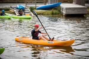 - un garçon en canoë-kayak orange sur l'eau dans l'établissement Adventure Lodges and Retreats, à Bideford