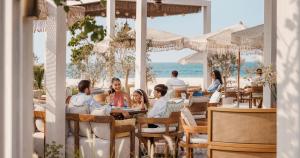 a group of people sitting at a restaurant on the beach at Jumeirah Beach Hotel Dubai in Dubai