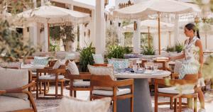 a woman standing in a restaurant with tables and chairs at Jumeirah Beach Hotel Dubai in Dubai