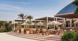 a restaurant with tables and umbrellas in front of a building at Jumeirah Beach Hotel Dubai in Dubai