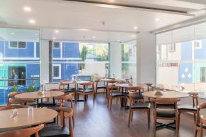 - une salle à manger avec des tables, des chaises et des fenêtres dans l'établissement Townhouse Reva College University, à Yelahanka