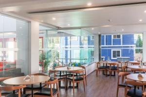 - un restaurant avec des tables, des chaises et de grandes fenêtres dans l'établissement Townhouse Reva College University, à Yelahanka