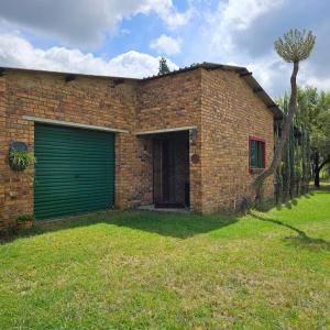 een stenen huis met een groene garage bij Villa Dachie in Rayton