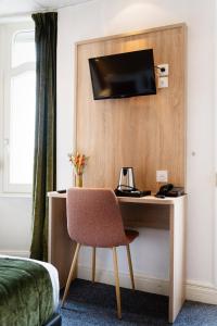 a hotel room with a desk with a television on a wall at Hôtel Escurial - Centre Gare in Metz