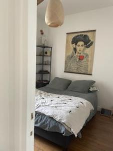 1 dormitorio con 1 cama y una pintura en la pared en Appartement cosy, en Le Perreux-Sur-Marne