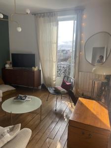 ein Wohnzimmer mit Tisch und großem Fenster in der Unterkunft Appartement cosy in Le Perreux-sur-Marne