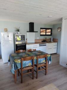 uma cozinha com uma mesa e cadeiras e um frigorífico em chalet la rose des sables em Labenne