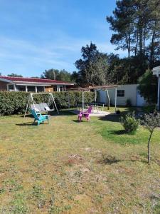 a yard with two chairs and a swing at chalet la rose des sables in Labenne