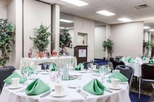 un salón de banquetes con mesas blancas y servilletas verdes en Ramada Plaza by Wyndham Albany, en Albany