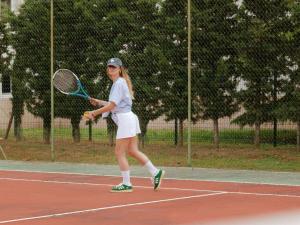 una donna che tiene una racchetta da tennis su un campo da tennis di Pullman Toulouse Airport a Blagnac