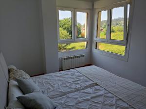 1 dormitorio blanco con 2 ventanas y 1 cama en Apartamento MAR y MONTAÑA ASTURIAS, en Posada de Llanes
