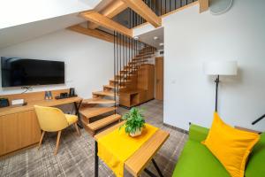 a living room with a green couch and wooden stairs at Willa Pod Kolejką in Szczawnica