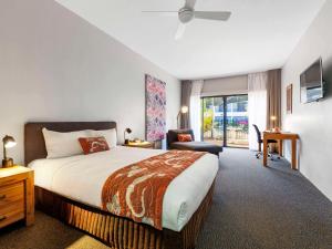 a bedroom with a bed and a chair and a window at Mercure Kakadu Crocodile in Jabiru