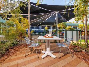 a white table with two chairs and an umbrella at Mercure Kakadu Crocodile in Jabiru