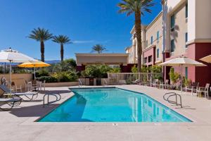 una piscina en un hotel con sillas y sombrillas en Hampton Inn & Suites Palm Desert, en Palm Desert