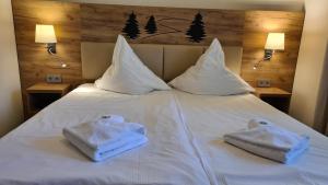 Una cama blanca con toallas encima. en Hotel Am Wald B&B, en Michendorf