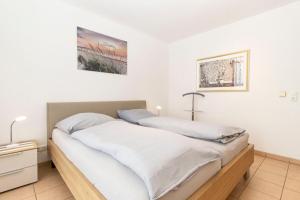 2 Betten in einem Schlafzimmer mit weißen Wänden in der Unterkunft Nordseeblick 5 in Cuxhaven