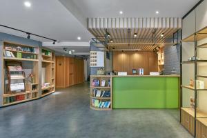 uma biblioteca com um balcão verde e prateleiras de livros em Atour Light (Chengdu Jinli) em Chengdu