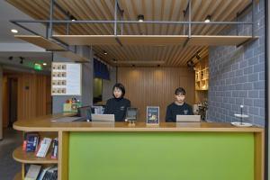 Dos mujeres sentadas en un mostrador en una biblioteca con ordenadores portátiles en Atour Light (Chengdu Jinli) en Chengdú