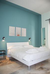 Cama blanca en habitación con pared azul en Le Sere, en Reggio Calabria
