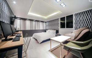 Schlafzimmer mit einem Bett und einem Schreibtisch mit einem Computer in der Unterkunft Cheese Hotel Seomyeon in Busan