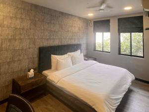 a bedroom with a large bed with white sheets at Backpacker Cowies in Mumbai