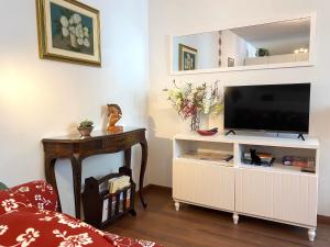 ein Wohnzimmer mit einem TV auf einem Stand mit einem Tisch in der Unterkunft Appartamento Palazzo Montegnacco-Braida in Udine